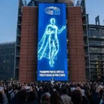 Pemimpin partai virtual berbentuk avatar digital sedang berpidato di layar raksasa gedung Parlemen Eropa.